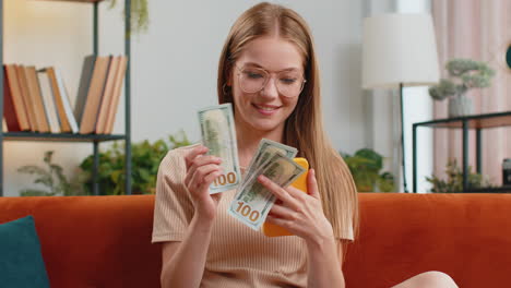 Mujer-Joven-Sonriente-Y-Feliz-Contando-Dinero-En-Efectivo,-Uso-De-Ingresos-Por-Teléfono-Inteligente,-Ahorra-Lotería-Y-Gana-El-Presupuesto-En-Casa