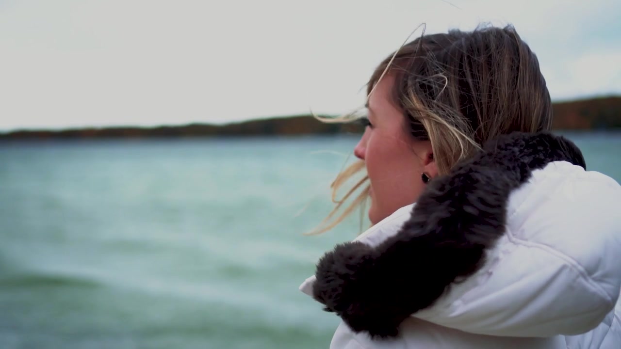 Young Woman Looking Out at Water with Hair Blowing in Wind