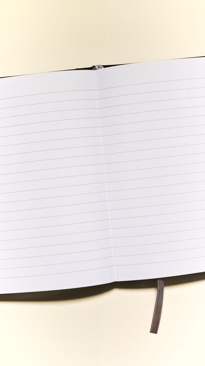 Portrait stop motion of stationery moving around an open lined notebook, leaving clear center copy space