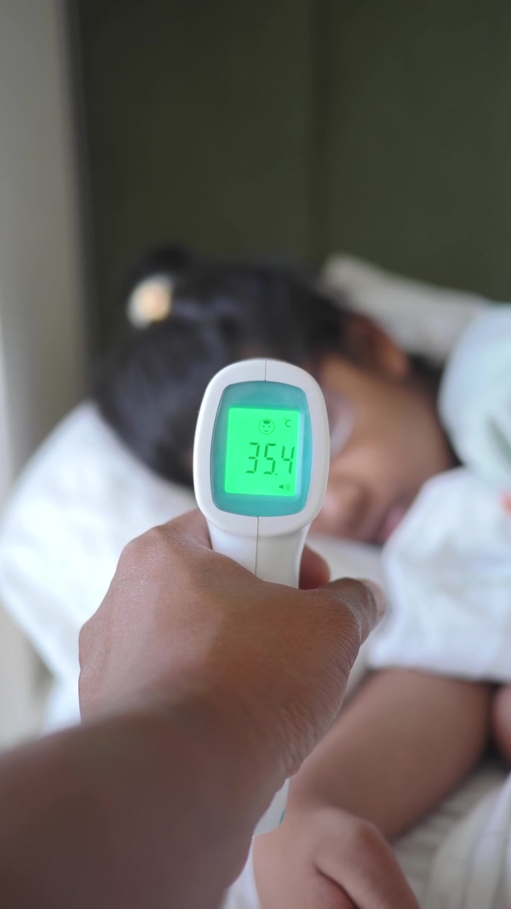 Genitore che controlla la temperatura del bambino che dorme con un termometro a infrarossi