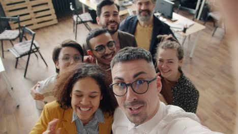 slow motion portrait of cheerful office workers taking selfie in workplace smiling looking at camera