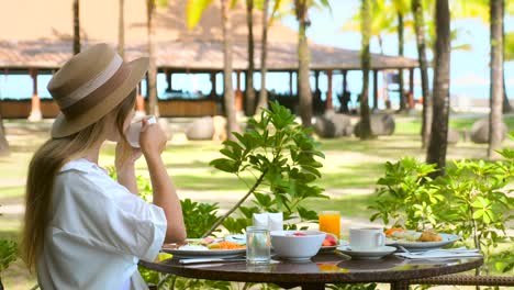 young woman drinking hot coffee in white cup at outdoor luxury resort restaurant