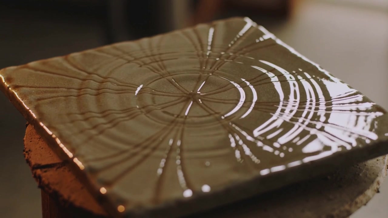 Turning banding wheel, glazed square ceramic tile spinning in ceramics studio making radial pattern