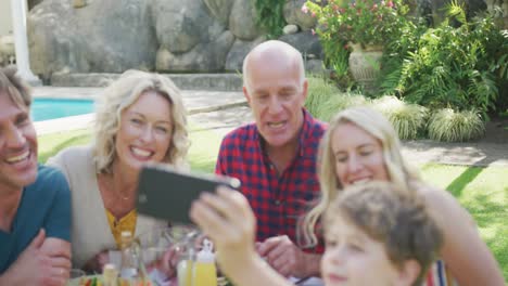 Feliz-Familia-Caucásica-Cenando-Y-Tomándose-Selfie-En-El-Jardín