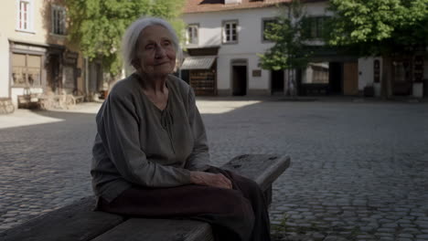 elderly woman sitting on a bench in a quiet town square