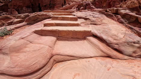 going up the stairs cut in the rock. walking inside the stunning canyon in ancient city of petra in jordan. al siq canyon.