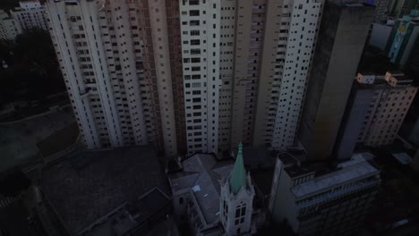 aerial tilt of a church and decayed apartments revealing the sunlit metropolis of sao paulo city