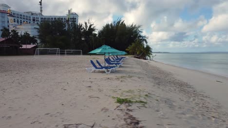 Low-angle-drone-shot-of-chairs-and-umbrellas-on-a-tropical-beach