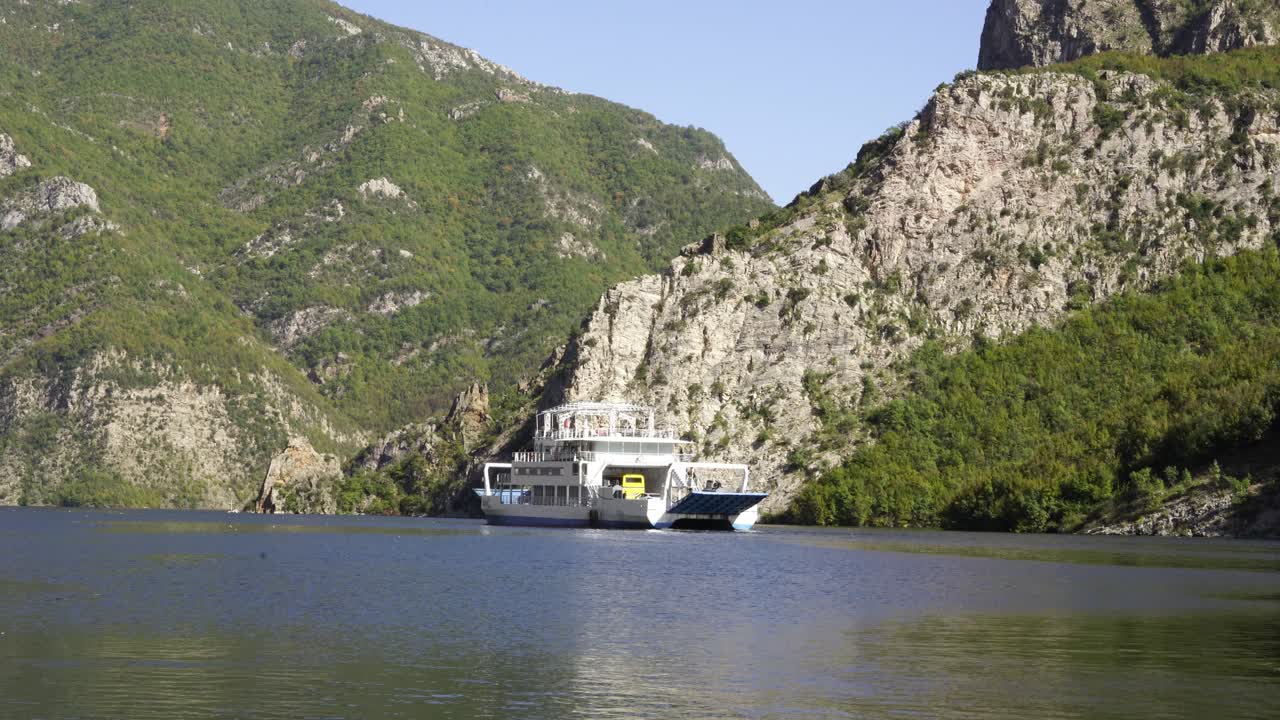 Narrow lake of Fierza, surrounded by high mountains with vegetation, ferry sailing across the valley on a fabulous tour in Albania