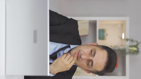 vertical video of home office worker man thinking depressed and feeling unhappy.