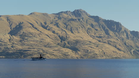 An-old-fashioned-steamboat-on-a-voyage-against-a-rugged-mountain-background