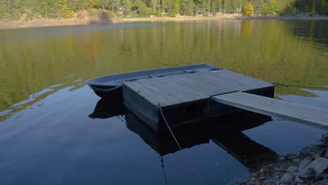 Disparo-Constante-De-Un-Embarcadero-De-Madera-Con-Un-Barco-Anclado-En-El-Lago-Local-En-Un-Día-Soleado-1