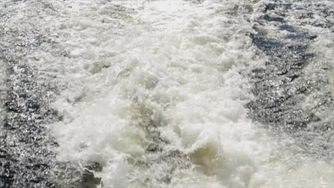 this is a shot of water churning from behind a boat as it travels around a lake