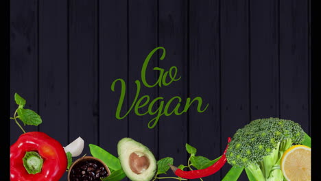 go vegan text over various fresh vegetables and dark wooden background