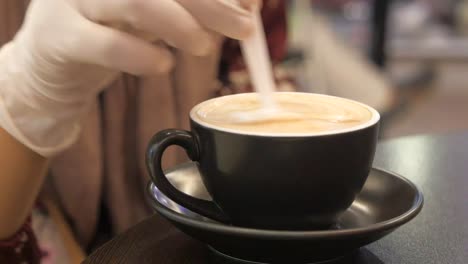 person with protective gloves stirring coffee