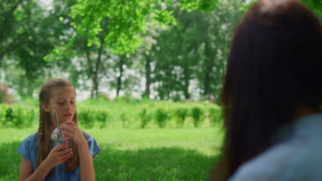 Tranquil-girl-holding-drink-on-picnic-close-up.-Child-taste-juice-on-nature.