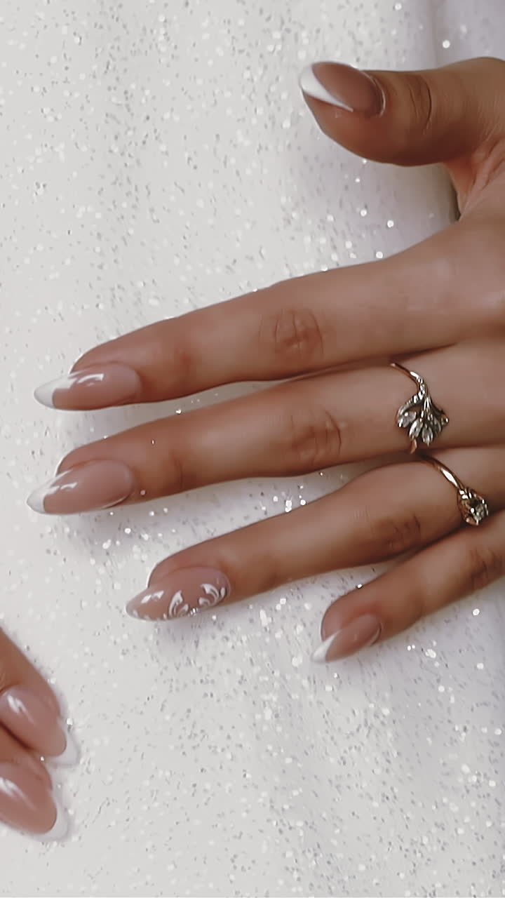 CU, slow motion: elegant bride wearing wonderful shining wedding dress shows hands with rings and pearl bracelet against skirt extreme close view