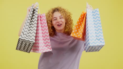 happy curly-haired woman holding shopping bags