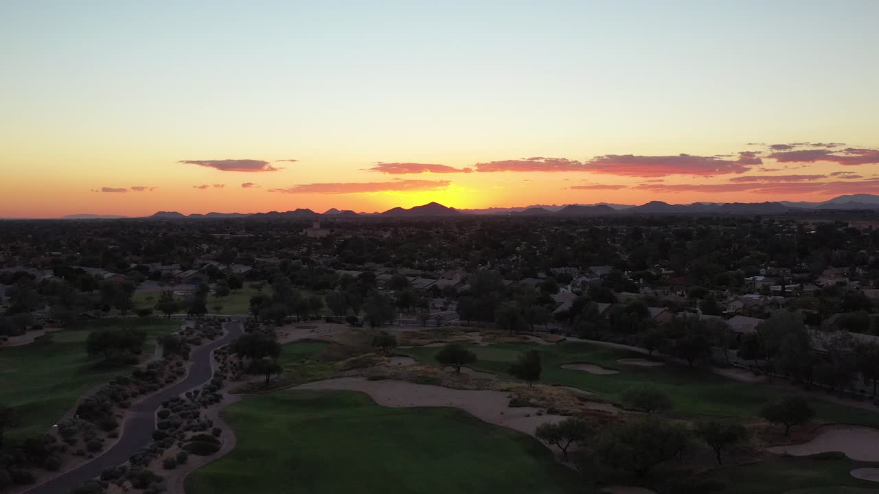 A drone glides along a golf course and raises up to reveal a stunning sunset aerial.
