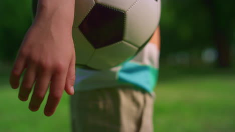 Mano-De-Niño-Desconocido-Sosteniendo-Un-Balón-De-Fútbol-De-Cerca.-Brazo-Infantil-Manteniendo-La-Pelota-En-La-Pradera.