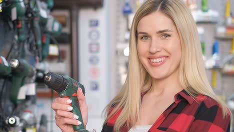 a woman with layered blonde hair is holding an electric blue drill in a store a woman with layered blonde hair and brown hair is holding an electric blue drill in a store she is wearing a tartan outfit and has a plaid eyelash on her thigh for a special event