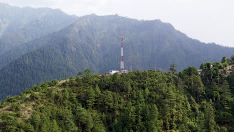 mobile tower in himalayan forested mountain, surrounded by lush greenery with a backdrop of misty peaks