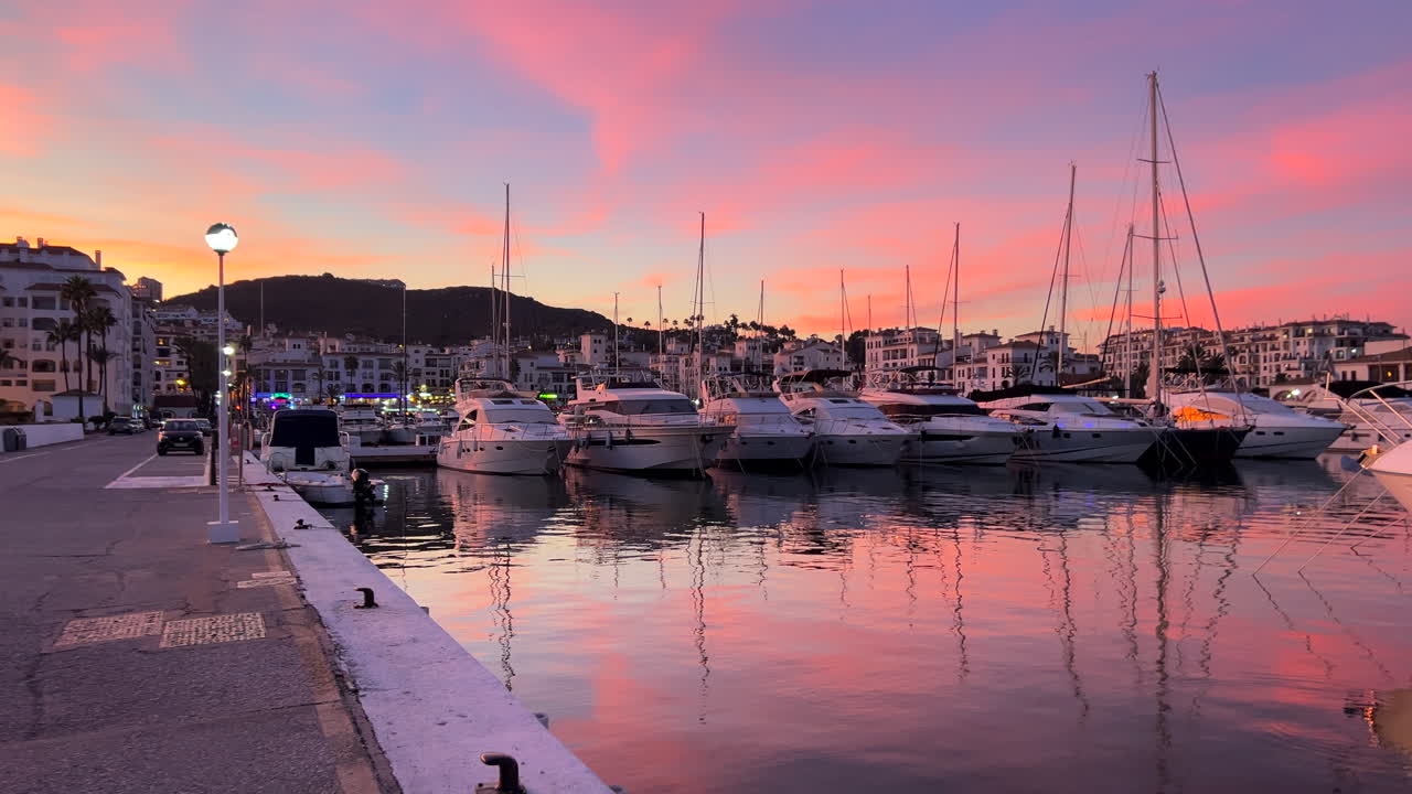 Beautiful pink sunset in port of Puerto de la Duquesa with luxury yachts and boats in Manilva, famous holiday destination in Spain, luxury lifestyle, pink sky and clouds, sea view, 4K shot