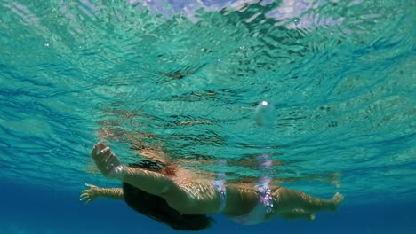 little red hair girl relaxes by floating with open arms and letting herself be lulled by sea movement