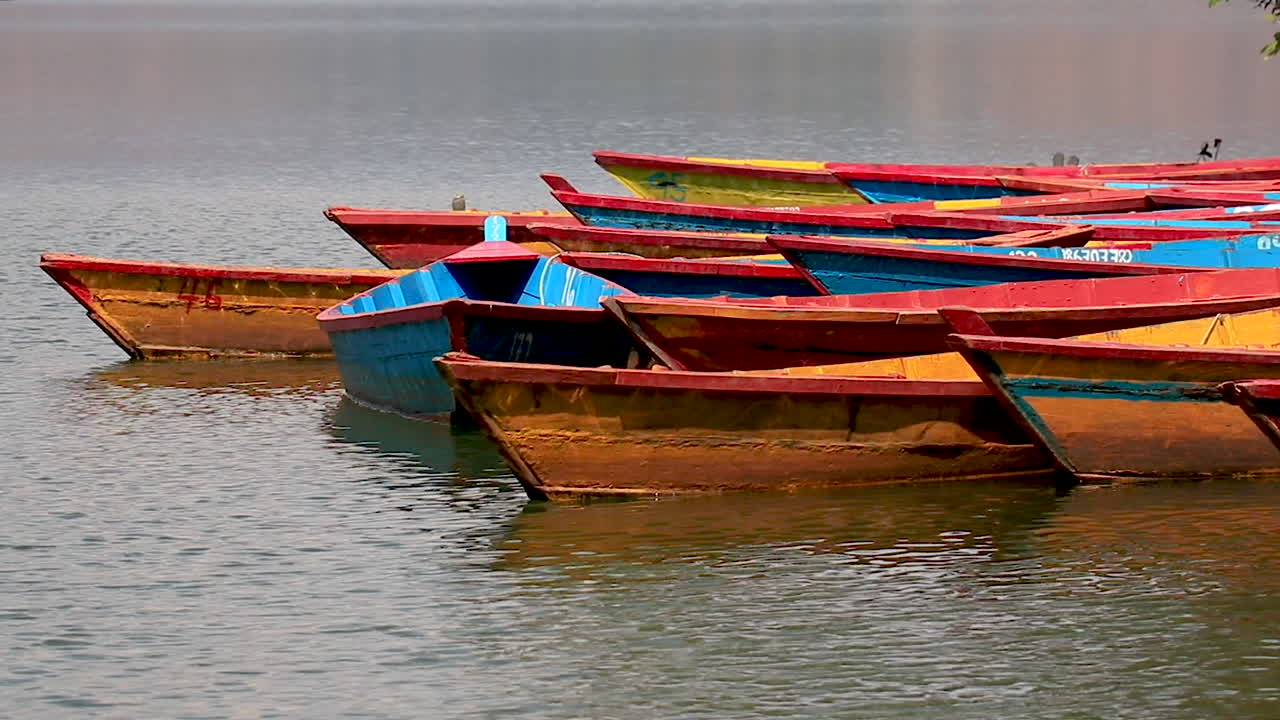 Colorful wooden boats in a lake. Traditional boats parked at the shore of Begnas Lake in Pokhara, Nepal.