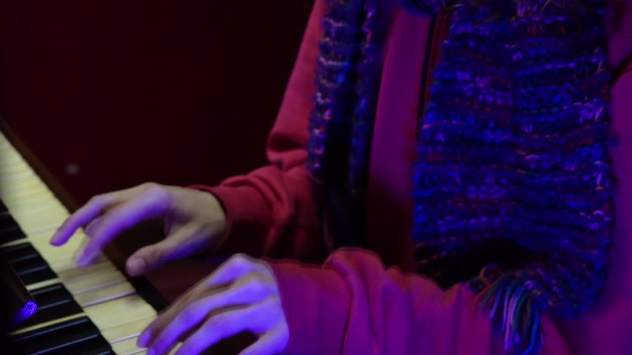 A heartwarming scene featuring a woman in red outfit and scarf playing music on a piano.