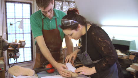 workers in bespoke shoemakers measuring template for last