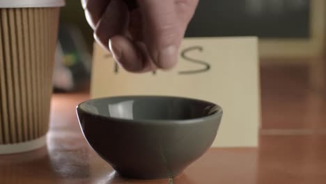 Hands-putting-coins-in-tip-jar-close-up-shot