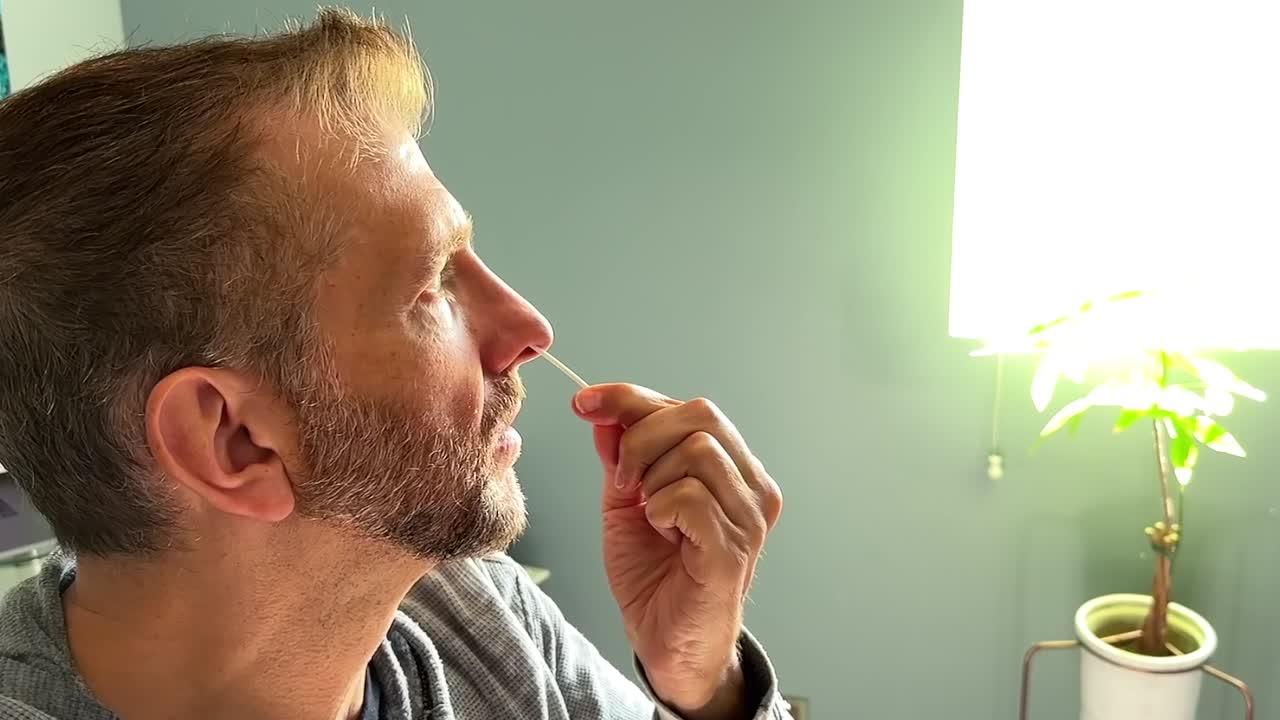 Uomo caucasico che esegue un test casalingo per il Covid-19, per verificare la positività ai sintomi del Coronavirus.