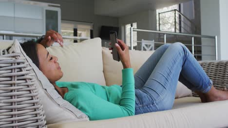 mujer de raza mixta acostada en el sofá teniendo video chat en el teléfono inteligente soplando besos