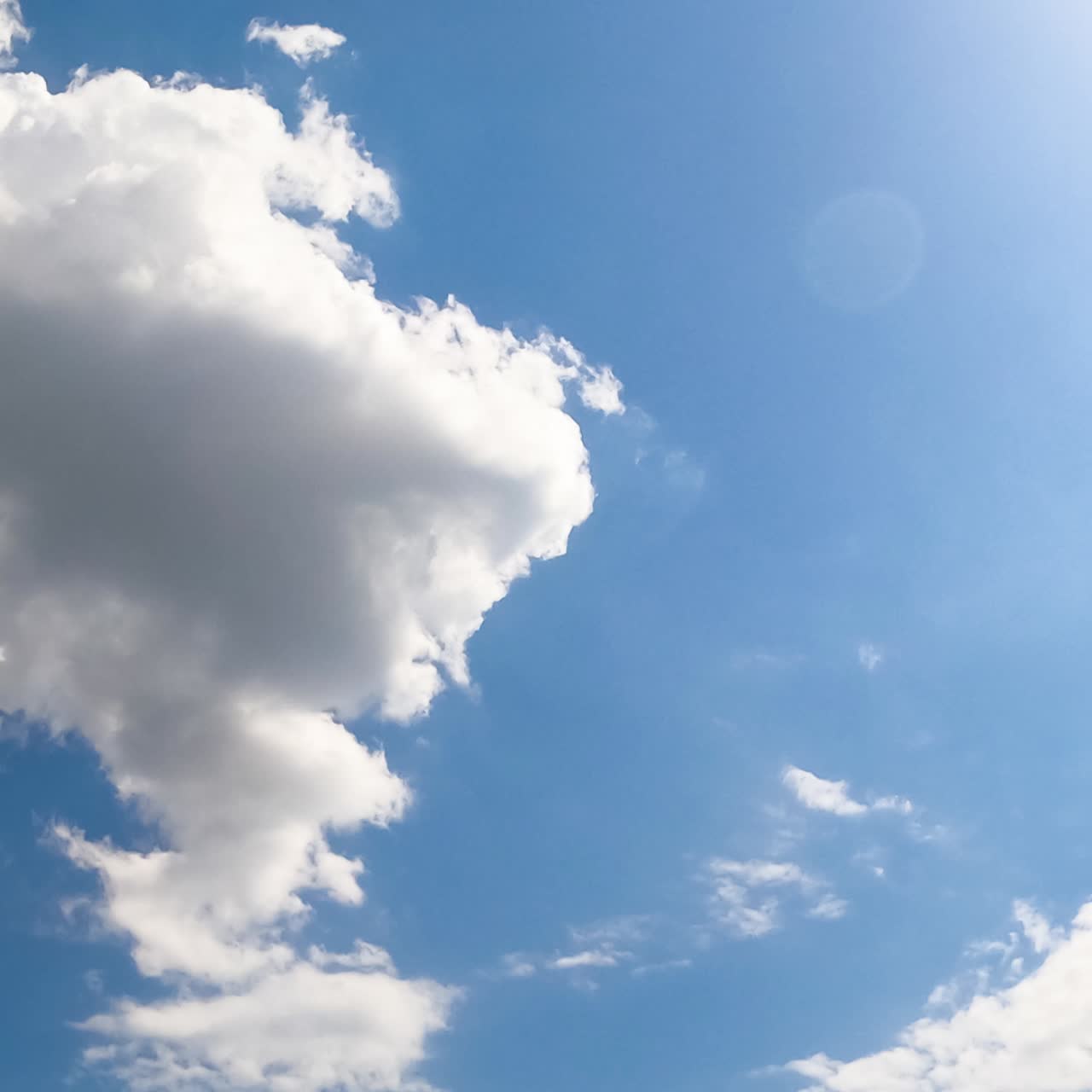 Sun lighting the cirrus clouds in the azure skies. Big grey cloud appears and covers the sky. Low angle view. Timelapse
