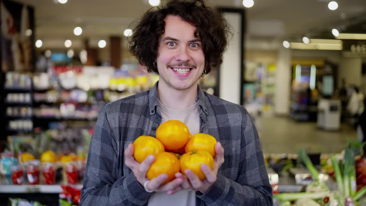 Portrait of a happy guy with curly hair in a plaid shirt holding yellow fruits in his hands in a supermarket while shopping at a grocery store