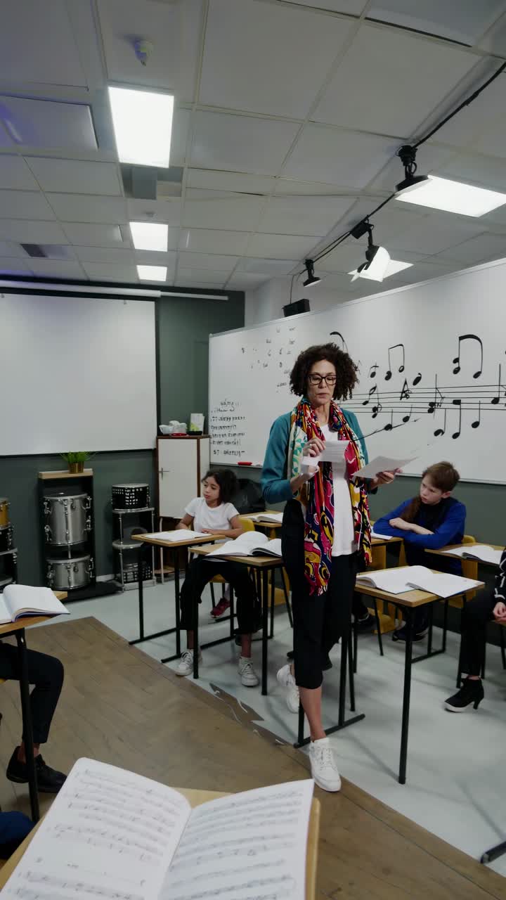 A music teacher instructs students in a classroom, captured from a low-angle
