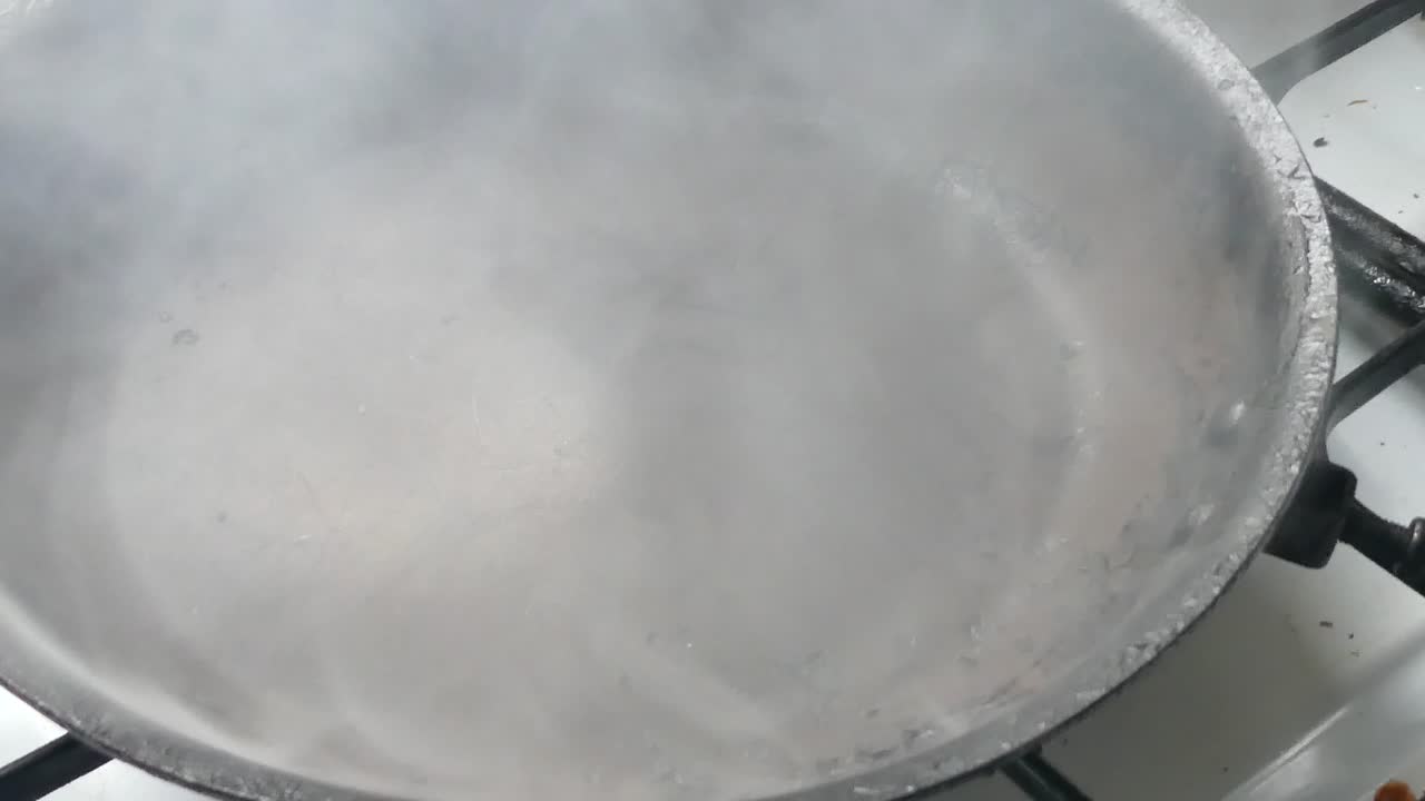 요리를 준비하기 위해 기름을 뿌린 검은 금속 불타는 연기가 나는 뜨거운 팬