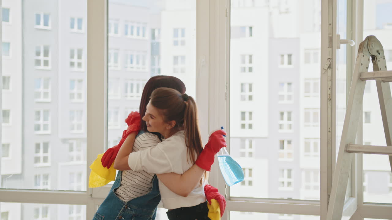 두 명의 여성이 함께 창문을 청소하고 있습니다.