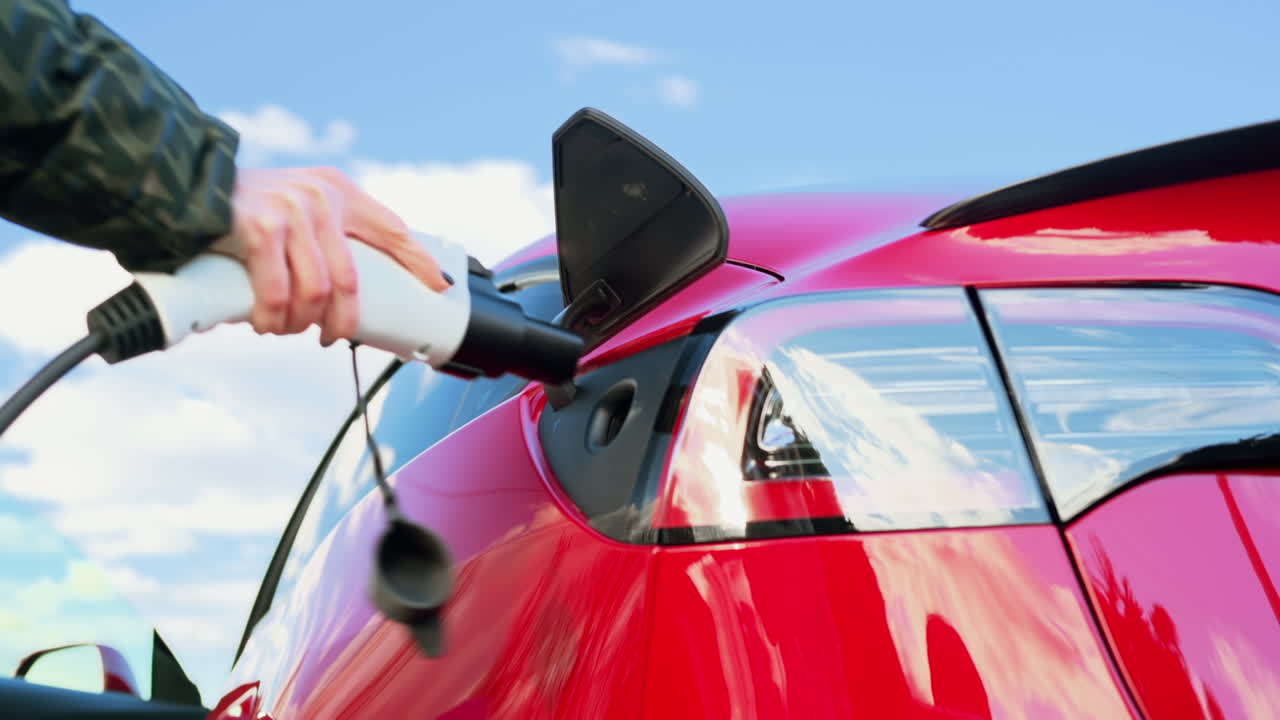 Close view of a woman plugging charger into her electric red car