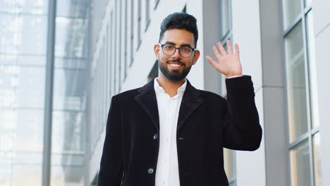 business man smiling friendly at camera, waving hands hello, hi, greeting or goodbye in city street