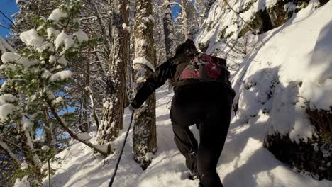 Young-woman-holds-rope,-hiking-up-snowy-mountain-hill-in-Norway,-slow-motion