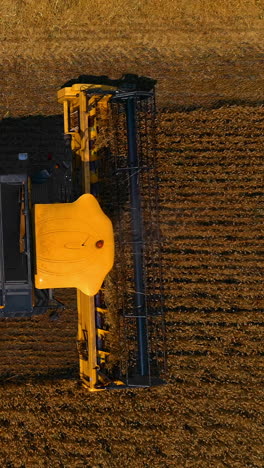 yellow combine is working on the large wheat field. heavy machinery harvests dry ripe wheat. agricultural concept. video from above. vertical video