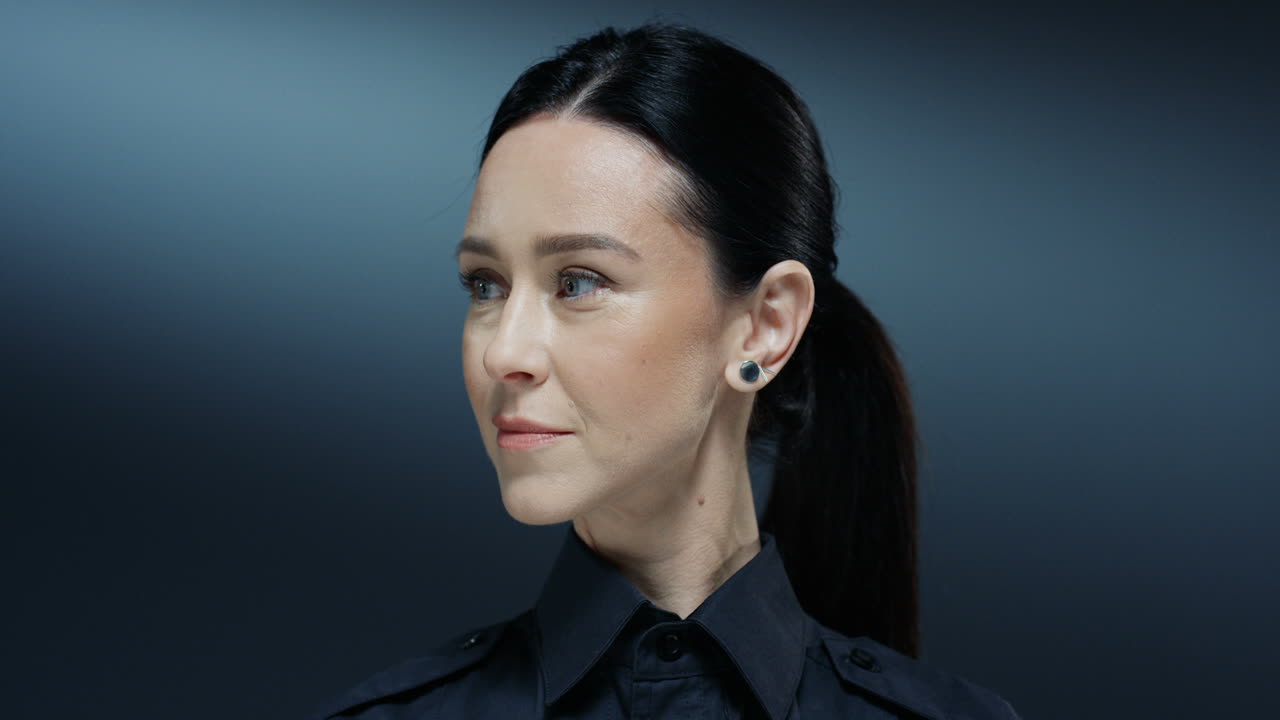 카메라에 얼굴을 돌리고 유쾌하게 웃는 경찰에서 젊은 아름 다운 갈색 머리 여자 닫습니다