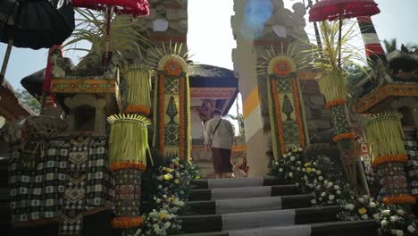 balinese man with sarong walk up decorated temple stairs, slow-motion