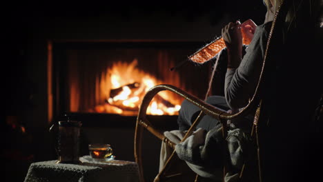 ocio de invierno - mujer teje sentada junto a la chimenea 4k video