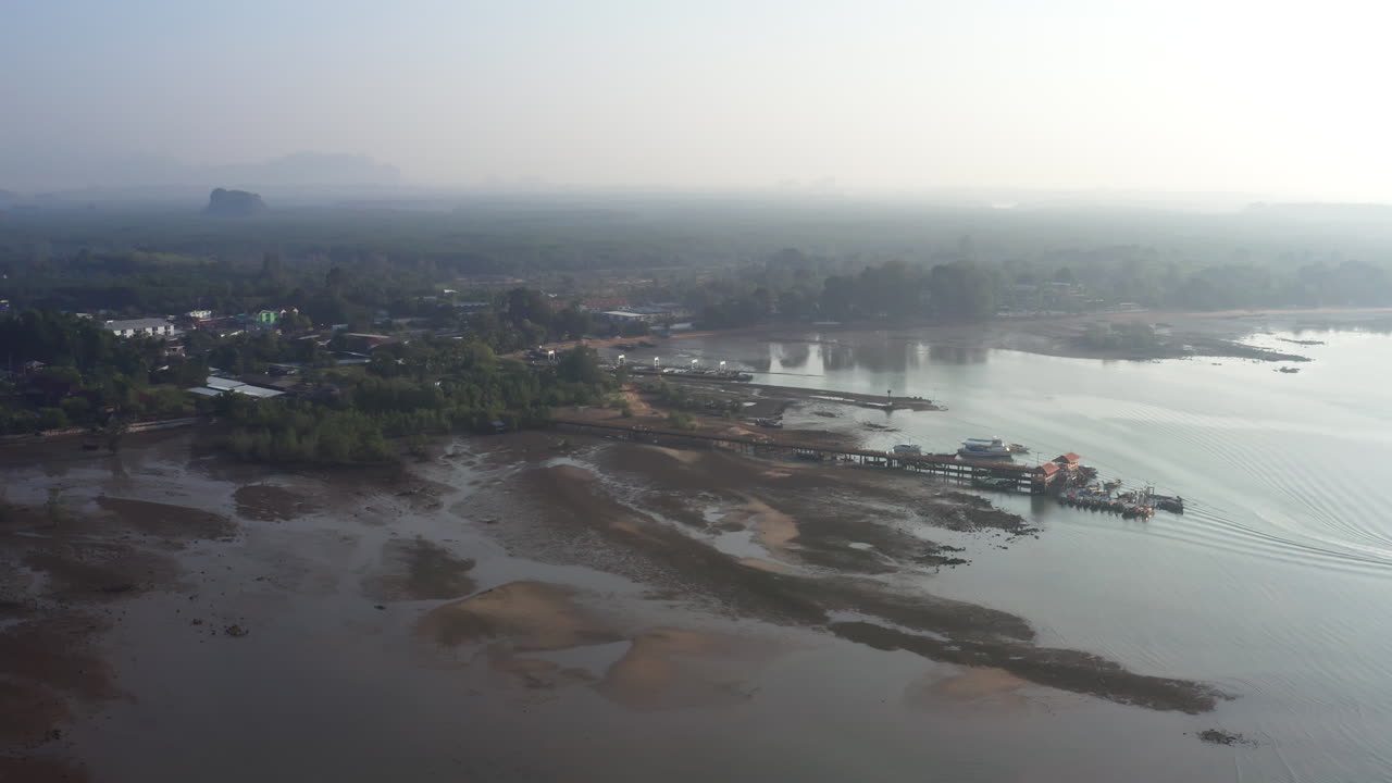 Costa marittima tropicale della Thailandia con un molo durante la bassa marea nella nebbia mattutina