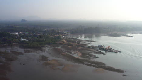 costa tropical del mar de tailandia con muelle en marea baja en la niebla matutina