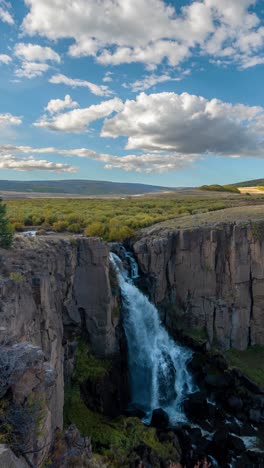 Vertikaler-4K-Zeitraffer,-Wolken-Ziehen-über-Wasserfall,-Klippen-Und-Sonnige-Landschaft