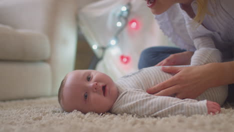 Liebevolle-Mutter-Spielt-Und-Kitzelt-Ihren-Kleinen-Sohn,-Der-Zu-Hause-Auf-Dem-Teppich-Im-Kinderzimmer-Liegt-–-Aufgenommen-In-Zeitlupe